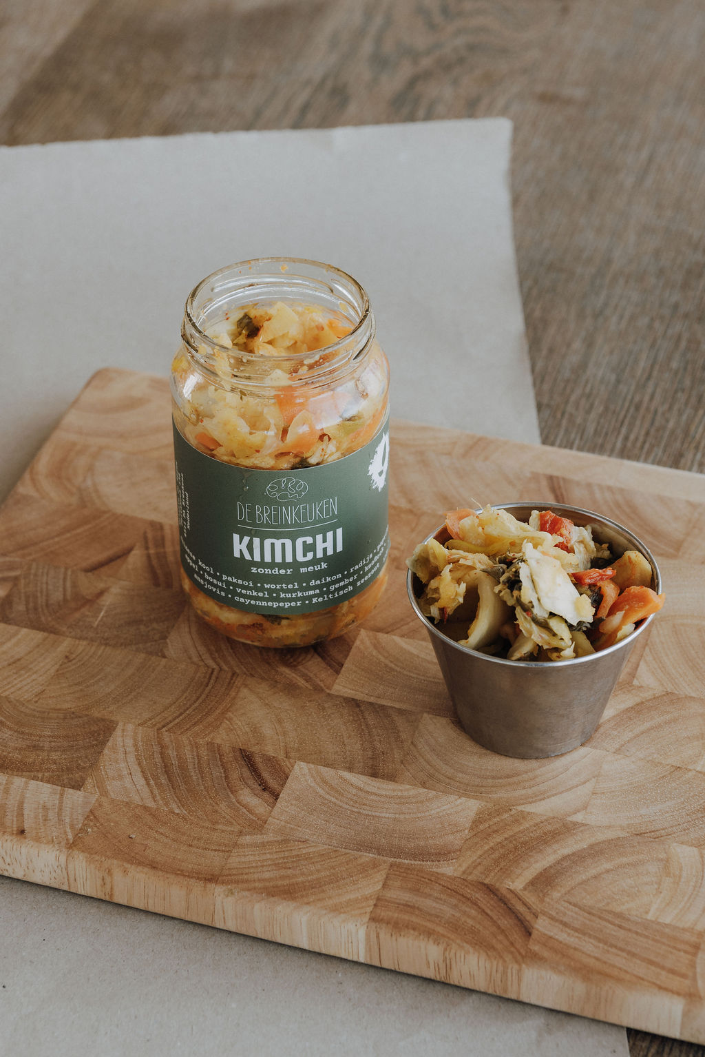 Pot kimchi van De Breinkeuken met een portie kimchi geserveerd ernaast op een houten plank